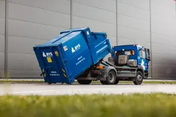 Niebieski kontener na śmieci na ciężarówce. Zastanawiasz się, ile kosztuje kontener na śmieci? Zapytaj BYŚ RECYKLING.